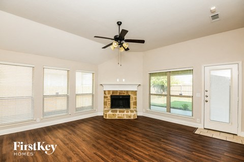 A spacious living room with a fireplace and a ceiling fan.