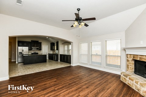 A spacious living room with wood flooring and a stone fireplace.