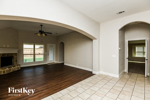 A spacious room with a fireplace and a fan on the ceiling.