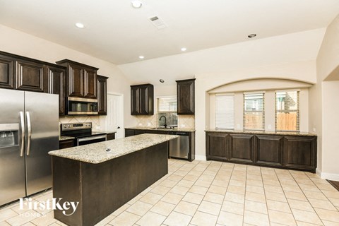 A kitchen with a refrigerator, oven, and cabinets.