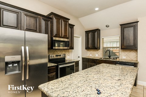 A kitchen with granite countertops and a stainless steel refrigerator.