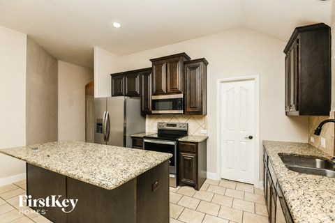 A kitchen with granite countertops and dark wood cabinets.