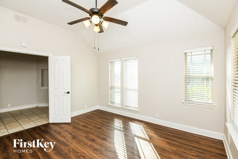 A room with a ceiling fan and wooden flooring.