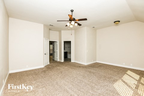 A spacious room with a ceiling fan and carpeted floor.