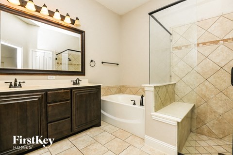 A bathroom with a large mirror, a bathtub, and a shower.