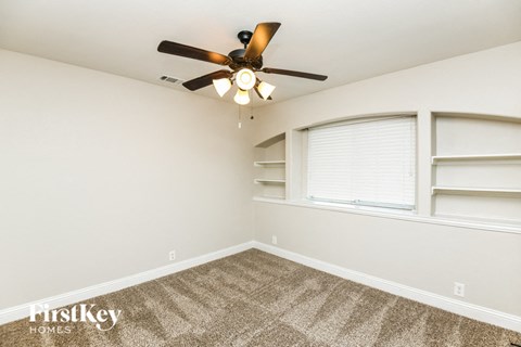 A room with a ceiling fan and carpeted floor.