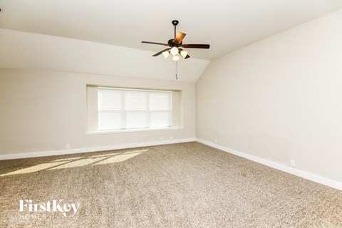 A room with a ceiling fan and a window with blinds.