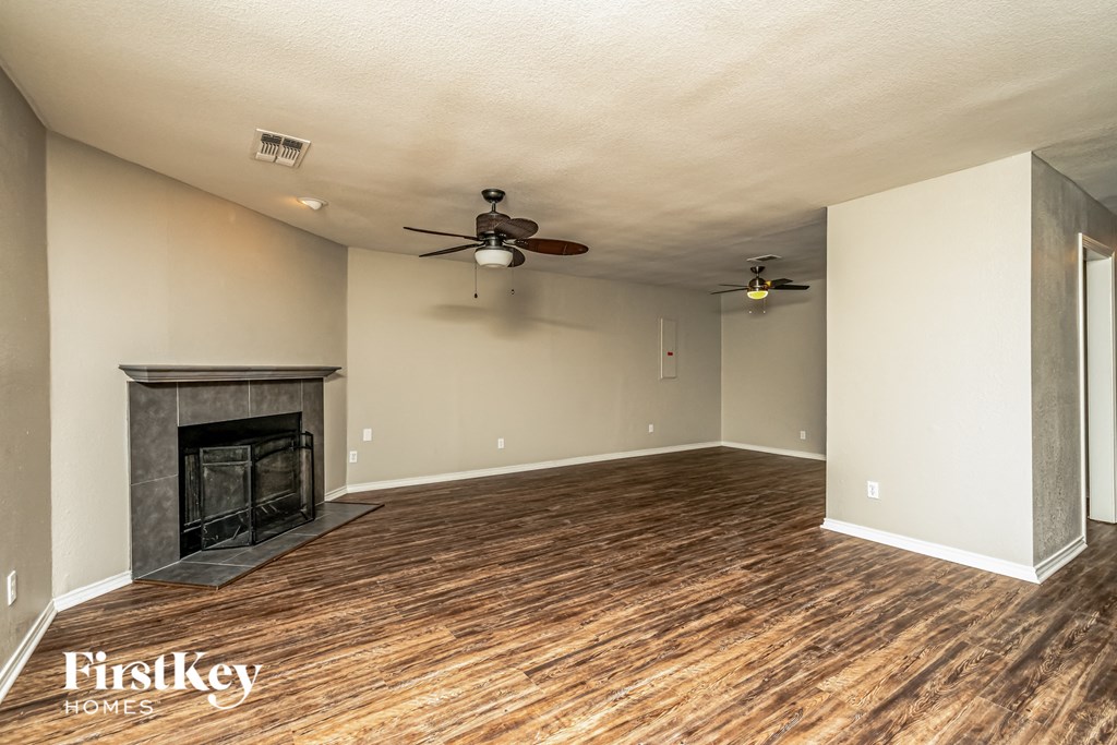 A spacious room with a fireplace and wood flooring.