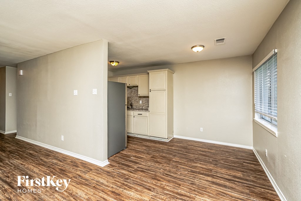 A room with wooden floors and a window with blinds.