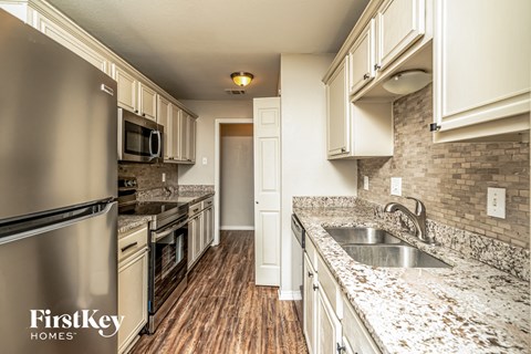 A kitchen with a stainless steel refrigerator and wooden floors.