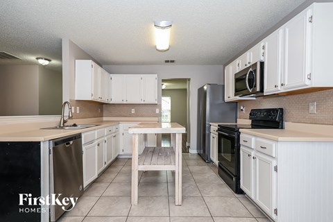 a kitchen with white cabinets and black appliances and a table