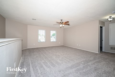 a living room with carpet and a ceiling fan