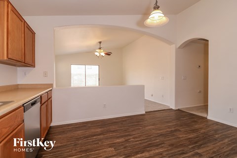 the kitchen and living room of an empty house with wood flooring