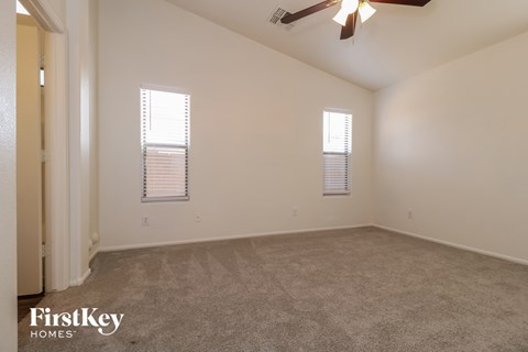an empty living room with two windows and a ceiling fan
