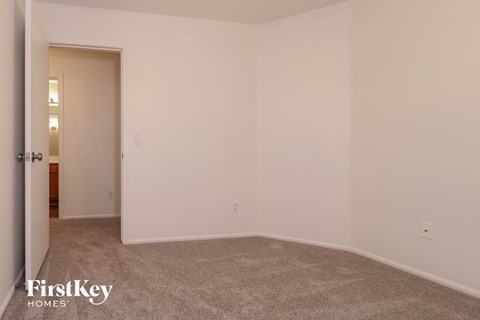 a bedroom with white walls and carpet and a door to a bathroom