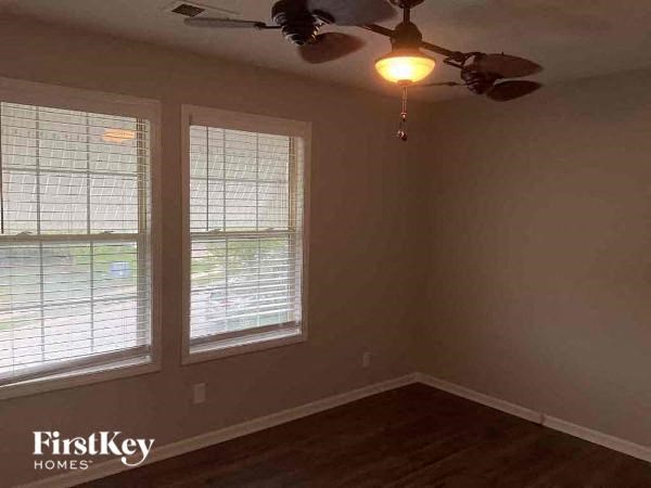 a bedroom with a ceiling fan and two windows
