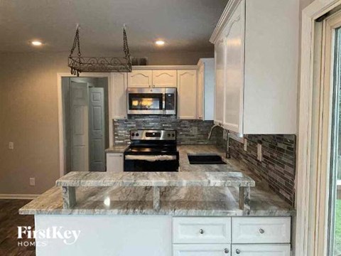 a kitchen with white cabinets and a marble counter top