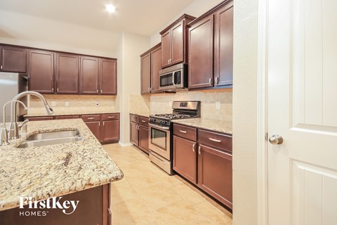 A kitchen with brown cabinets and a granite countertop.