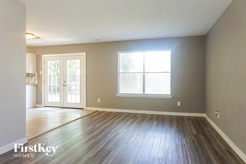an empty living room with wood floors and a window