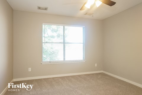 a bedroom with a large window and a carpeted floor