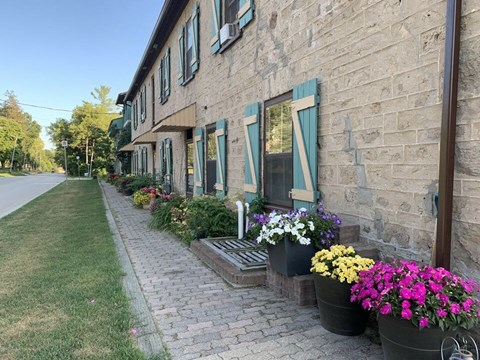 A row of flower pots line the sidewalk in front of a building.