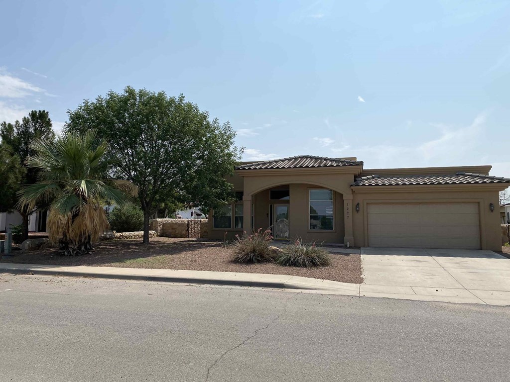 A house with a garage and a driveway in front of it.