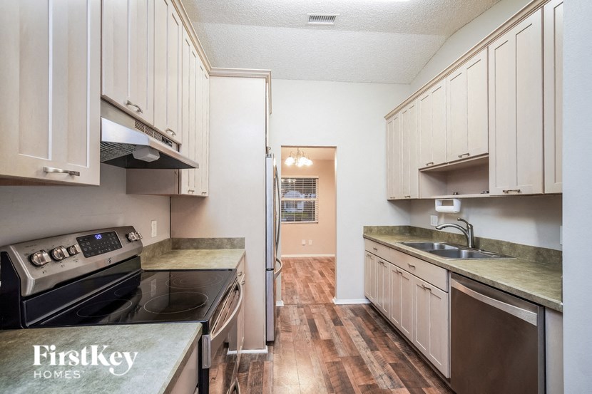 A kitchen with wooden floors and white cabinets.