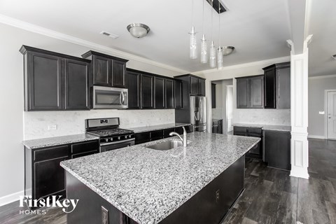 A kitchen with a granite countertop and black cabinets.