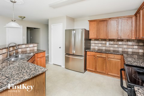 A kitchen with a granite counter top and wooden cabinets.