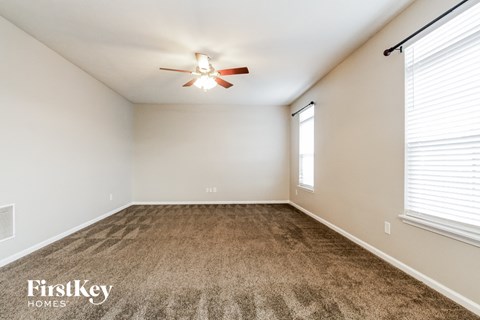 A room with a carpeted floor and a ceiling fan.