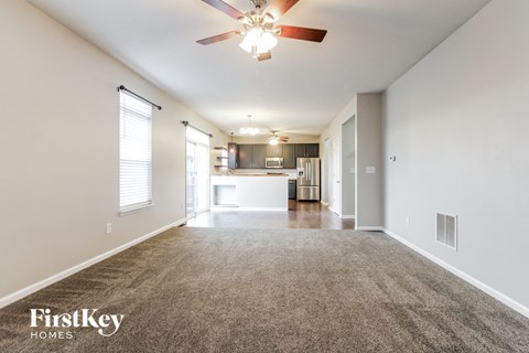 A spacious room with a carpeted floor and a ceiling fan.