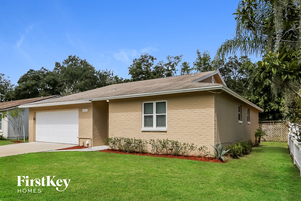 a small tan house with a lawn and a white garage door
