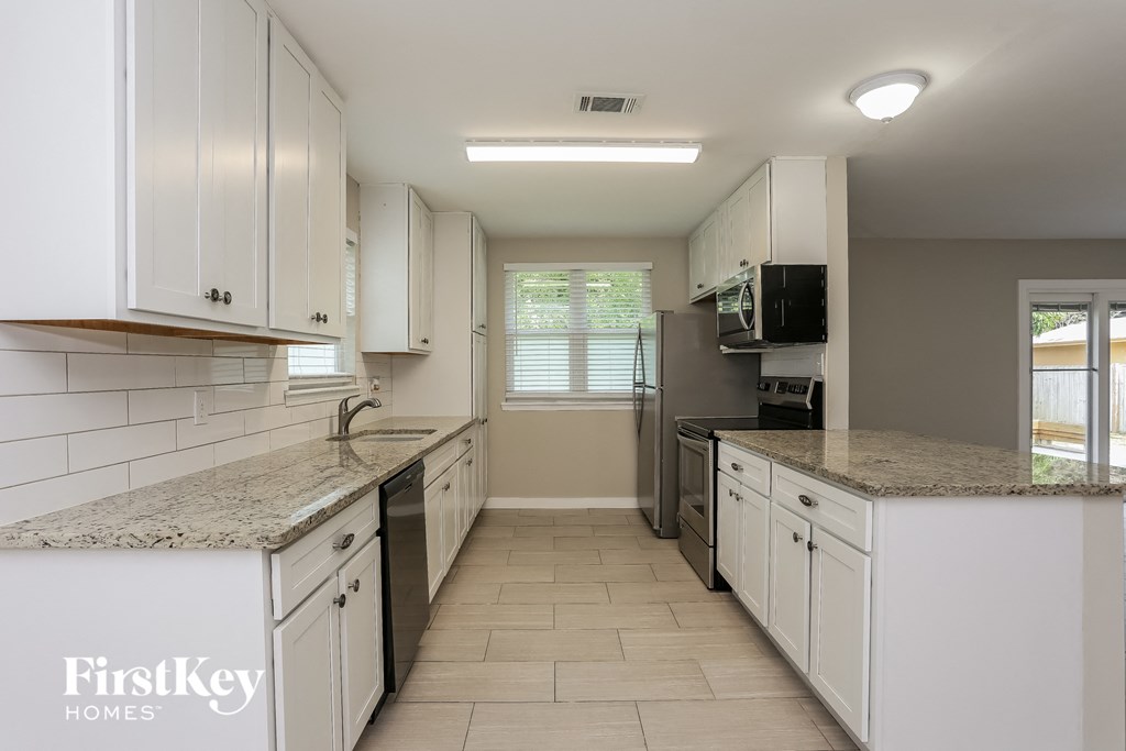 a kitchen with white cabinets and granite counter tops and white appliances