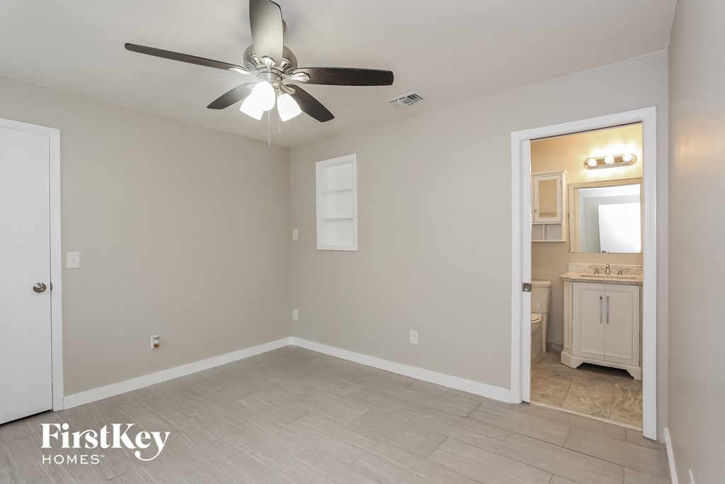 an empty room with a ceiling fan and a bathroom