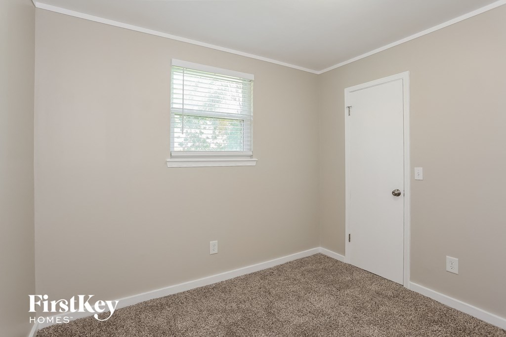 a bedroom with carpet and a window and a door