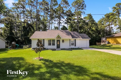 a small white house with a grassy yard and trees