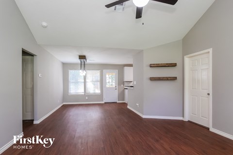 an empty living room with wood flooring and a ceiling fan