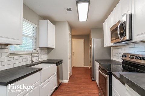 a kitchen with white cabinets and black counter tops and a stainless steel refrigerator and microwave