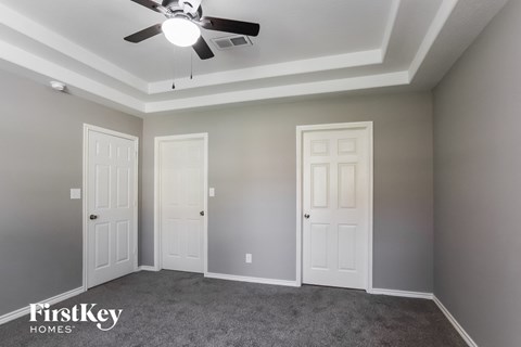 a bedroom with two doors and a ceiling fan