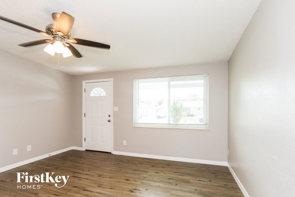 an empty room with a ceiling fan and a window