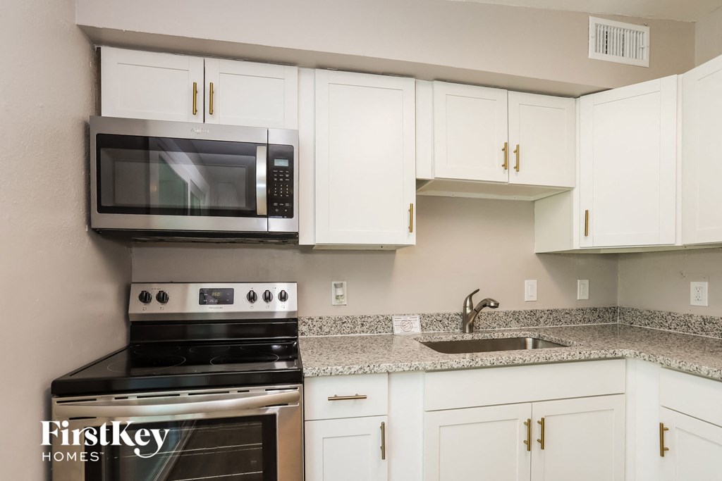 a kitchen with white cabinets and a stove and a microwave