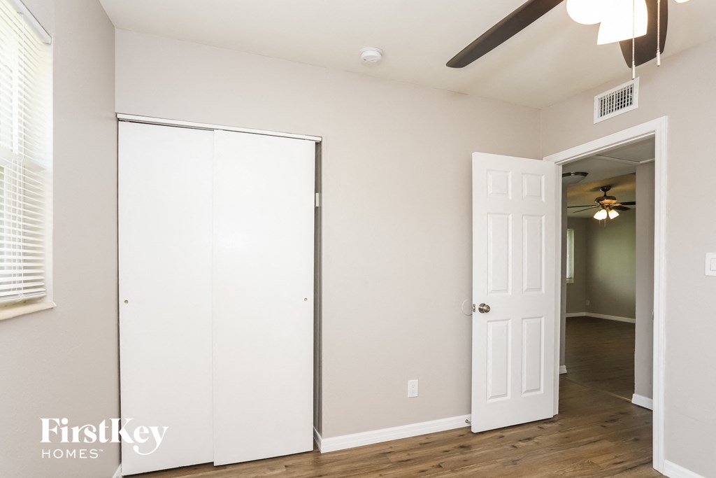 a bedroom with a closet and a door to a hallway and a ceiling fan