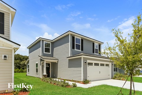 a gray house with a garage and a lawn