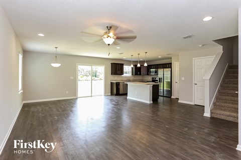 an empty living room and kitchen with a ceiling fan