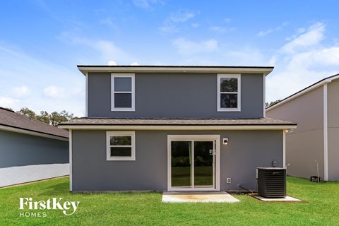 the exterior of a gray house with a lawn and a trash can