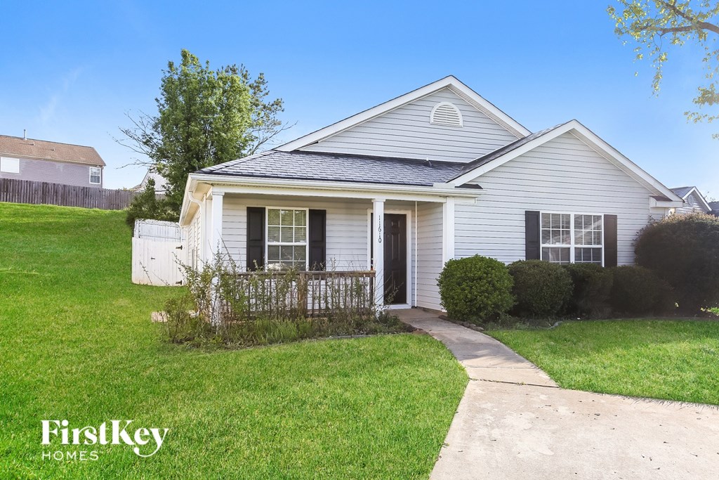 A house with a white front yard and a sidewalk leading to the front door.