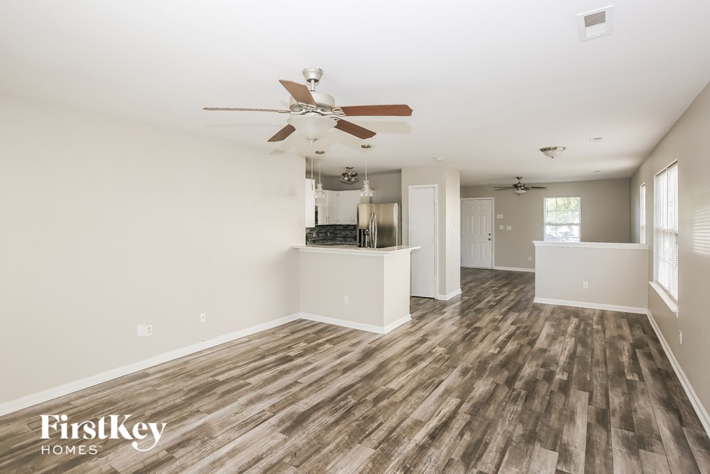 A spacious room with wooden flooring and a ceiling fan.