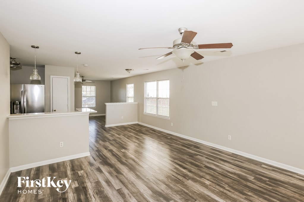 A spacious room with a fan and wooden flooring.