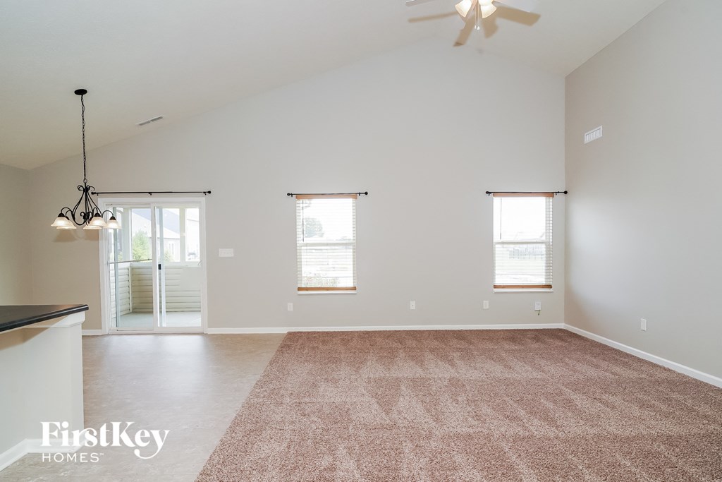 A spacious room with a carpeted floor and a ceiling fan.