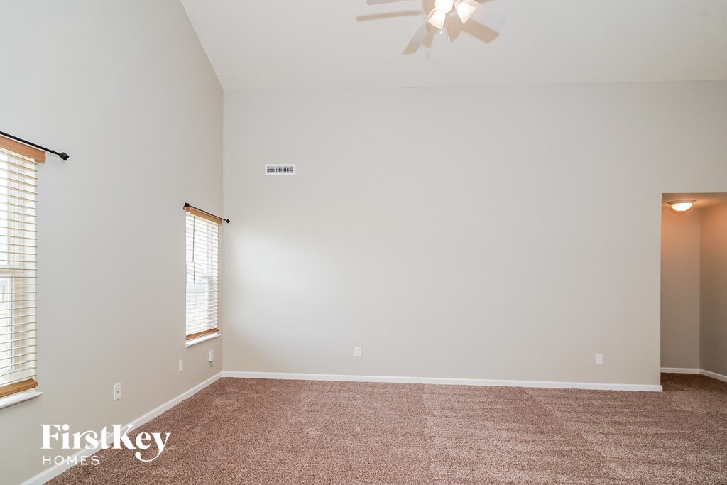 A room with a carpet floor and a ceiling fan.